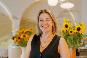 Close up image of Betul Kinalilar with a welcoming smile, at the bar area of Troya Mediterranean
