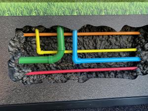 Underground utility line cutaway on the back wall of the Dig Smart Mobile Learning Center.