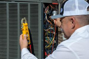 HVAC Service Technician is testing volts in heat pump