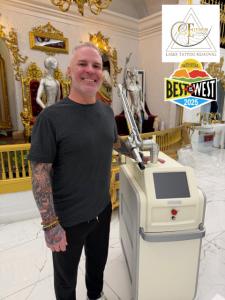Paul Wallis, owner of Elysium Laser in Grand Junction, Colorado, standing next to a PicoWay laser tattoo removal machine inside the studio