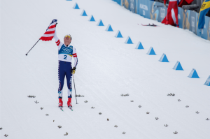 U.S. cross-country skier Ben Ogden skis with the American flag as he earns 2026 Olympic Winter Games in Milano Cortina.