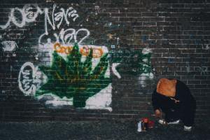 COCO the founder of Kommerce in 2012 as a young street artist and graphic designer living in New York posing in front of his friends graffiti tag.