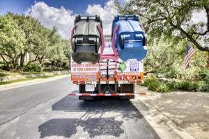Texas Scrub Hub service truck lifting and cleaning two residential trash cans in a San Antonio neighborhood.