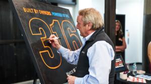 A man signs a black canvas at a business event.