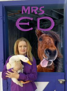 post or a smiling blond lady, holding a duck, with a horse