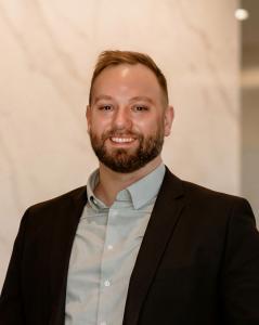 Professional headshot of Phil Neil, founder of Founders Compass and TEDx speaker, wearing a dark blazer and light blue shirt.