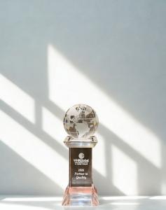 Physical WHR Partner in Quality Award, presented to Suite Home Corporate Housing, glass award with globe on top on white background.