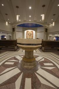 3D rosette in terrazzo anchors the baptismal font of the church