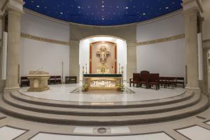 The altar in the front of the church with three terrazzo steps with dark edging.