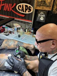 Brad Fink tattoo artist and FINK Caps creator tattooing at convention