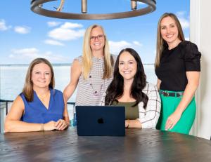 The McKellar Group Real Estate Team on the balcony of a luxury home with the lake behind them.