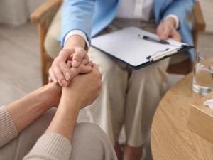 therapist holding patient hands during addiction counseling session in a clinical setting