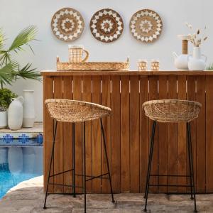 Rattan bar stools with metal legs at outdoor teak bar by pool