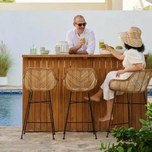People seated on rattan bar stools at poolside teak bar counter
