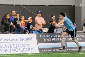 Detroit Metro FC player celebrating a goal at home in front of sponsor boards at Legacy Center Sports Complex, Brighton Michigan