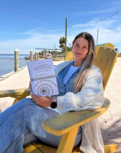 Holistic healing author Kateryna Armenta holding her book “30 Days of Transformative Holistic Healing” in Panama City Florida