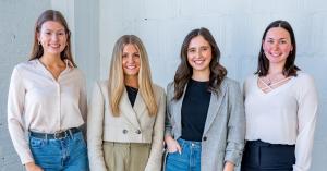 Four members of the 316 Strategy Group social media team pose together in an office. Bailey Quarles, director of social media, stands second from the right in a black top and gray blazer.
