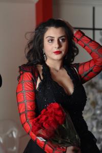 Tamara Mechael holding red roses during a professional portrait session, wearing a black and red outfit, photographed by Tyler Disney.