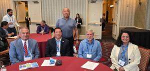 Nathan Hart (Kamaka Global), Reggie Wassana (Governor, Cheyenne and Arapaho), Karl Gee (Kamaka Global), Kevin Wolf (CEO, Wind Harvest), Pronita Saxena (CDO, Wind Harvest) sitting at a table at RES 2026