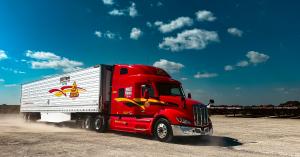 A Decker Truck Line tractor‑trailer in motion on an open yard under a bright blue sky