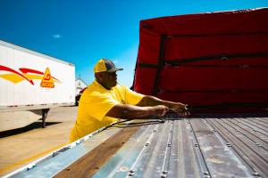 A Decker Truck Line team member securing cargo on a flatbed trailer