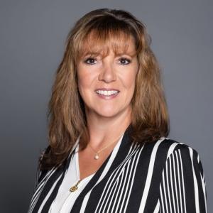 Professional headshot of Michele Vernola in a black and white striped blazer