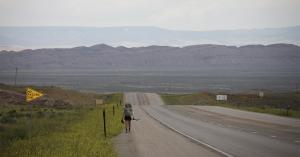 Continental Divide Trail hiker walking down a highway near Rawlins, Wyoming.