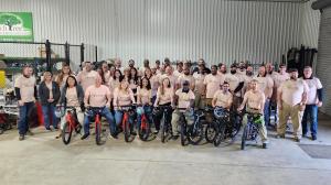 Peachtree leaders stand together, wearing their volunteer shirts while posing with newly assembled bicycles lined up in front of them.