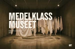 Pressbild för Medelklassmuseet som visar en installation av upphängda vita textilier i ett mörkt utställningsrum.