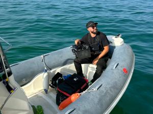 ORBIS Production camera operator on a boat during a specialty filming setup on open water.