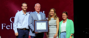 Three representatives from Harvest Community School with IBCCES CEO Myron Pincomb holding an award plaque during the ACSW handover ceremony.