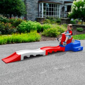 A young child playing on a red, white, and blue miniature rollercoaster.