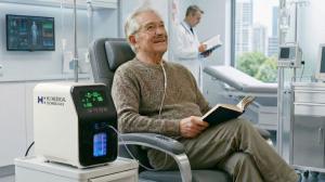Older patient seated in a clinic beside an H2 Medical Technologies molecular hydrogen device, illustrating supportive care for cognitive decline and age-related conditions