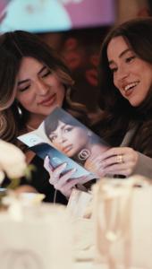 two girls looking at marketing materials in goodie bag from dinner event