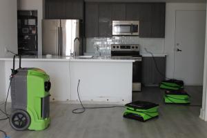SERVPRO green industrial dehumidifier and air mover drying equipment set up in water damaged kitchen in Naples Florida home during professional water damage restoration and dry out service