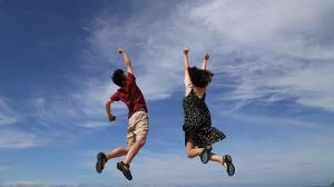 Couple outdoors, jumping for joy, enjoying a healthy, happy relationship and lifestyle.