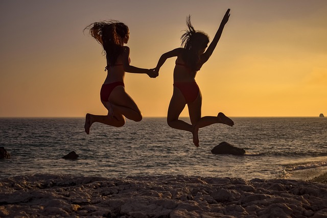 Two women outdoors, jumping for joy, radiating confidence, health, and happiness.