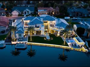 Luxury exterior holiday lighting installed on a Scottsdale waterfront estate with illuminated rooflines, palm trees, and landscape borders.