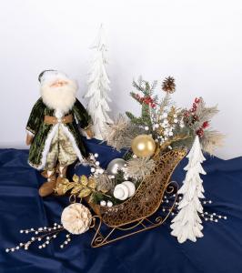 Elegant interior Christmas décor display with Santa, a gold sleigh centerpiece, frosted greenery, and white decorative trees.