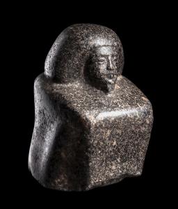 Egyptian New Kingdom to Late Dynasty carved black granite block figure, circa 1550-736 B.C., 8 inches tall, depicting a squatting figure with arms resting on his drawn-up knees. Sold for $10,000