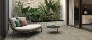 Une terrasse extérieure avec un carrelage imitation bois, un petit canapé, une table basse, des plantes