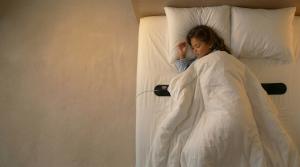 8 year old child on bed sleeping on top of Ozi Sleep Tracker. For position of sleep tracker. For position and placed under bed sheet when using