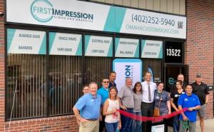 The team of First Impression Signs and Graphics standing in front of the new shop for the ribbon cutting.