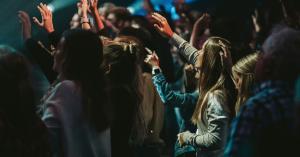 Group of people raising their hands during a worship gathering.