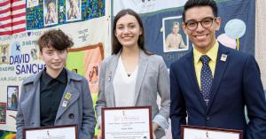 Young scholarship recipients holding award certificates in front of the AIDS Memorial Quilt