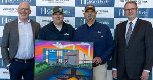 Representatives from Simplot Grand Forks accept the 2026 Klaus Thiessen Impact Award, a painting from local artist.