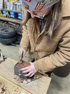 Emily Kempin ’26 uses a brass sand-cast to make the blade's fox pommel and crossguard.
