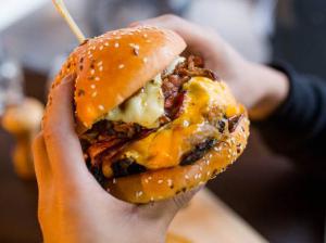Very large hamburger dripping with cheese and bacon and more cheese, more beef and more bacon