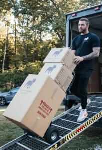 Bulldog Movers crew member unloading branded moving boxes from a truck ramp in Rockville, MD — professional local movers handling fragile dish pack items with care