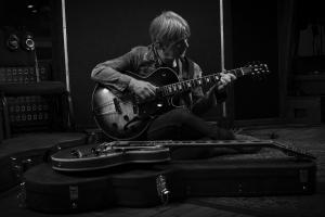man sits hunched over guitar in bw shot